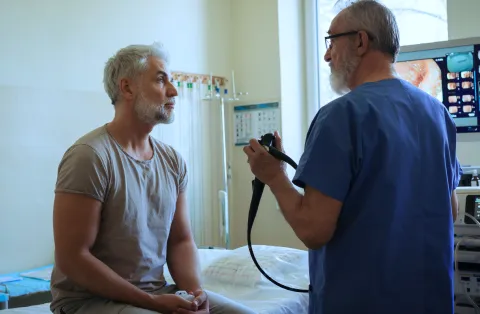 Gastroenterologist speaking with a patient about an endoscopy procedure in an exam room